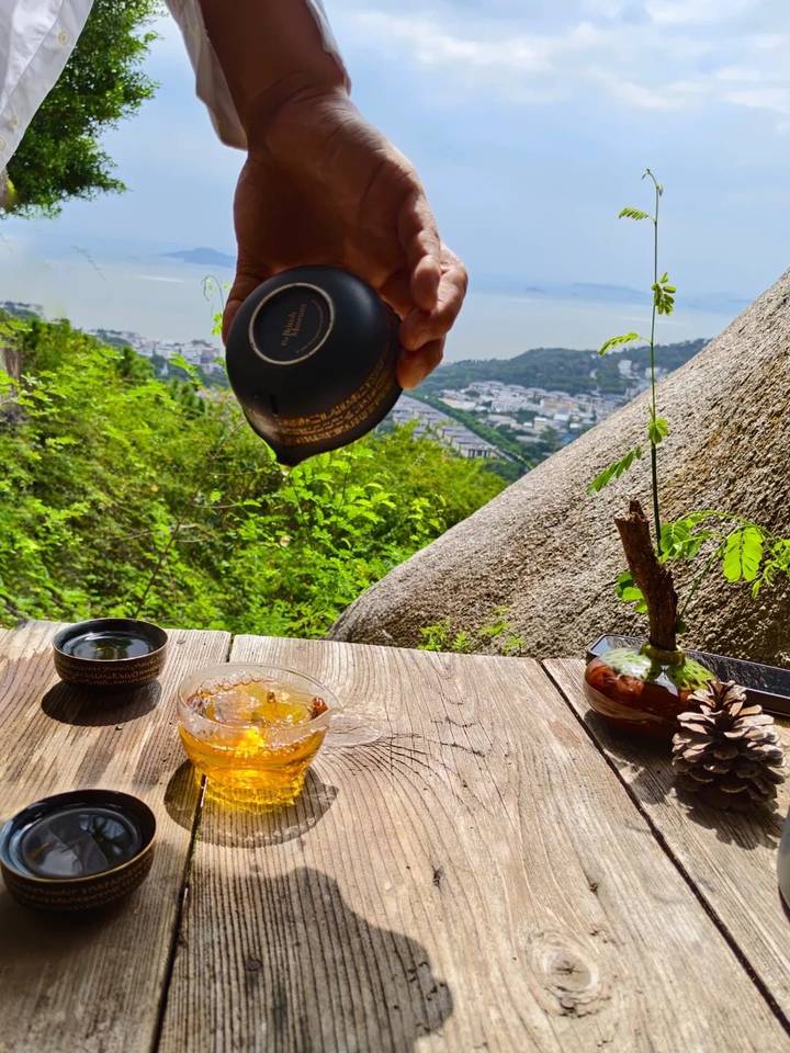 远眺山海的户外茶席与正在斟入杯中的茶汤